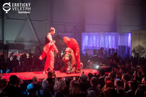 Pódiová performance v červených kombinézách nad davem s mobily, ročník 2022