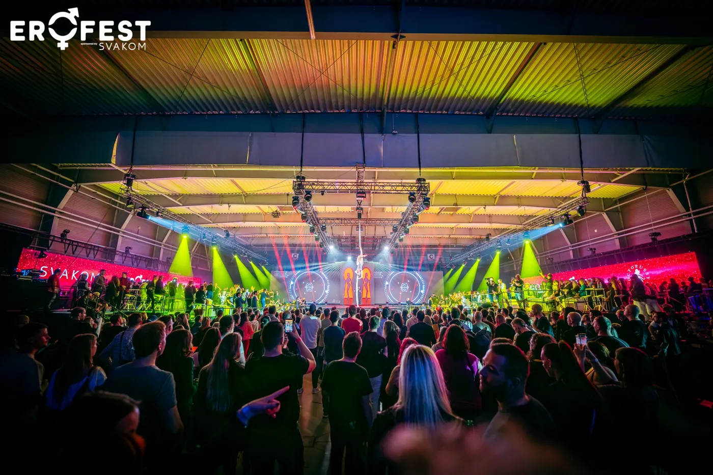 Zaplněná hala před hlavní stage v barevných světlech reflektorů